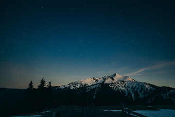 Snowy meadow, snowy mountains and stars in the background