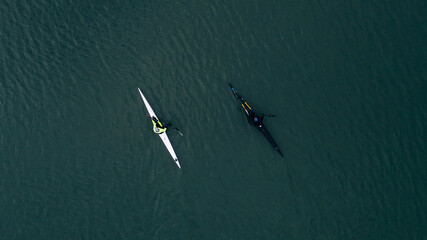 Top view of training of two men on kayaks floating on river water at sunny day