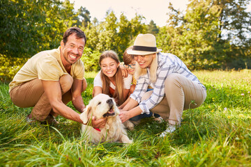 Fototapeta premium Kinder und Eltern streicheln gemeinsam Hund