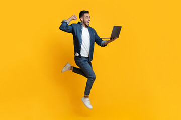 Fototapeta na wymiar Emotional arab guy using new modern laptop over yellow