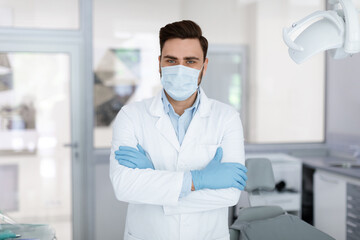 Fototapeta na wymiar Male doctor in face mask standing at dental clinic