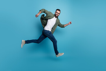 Fototapeta na wymiar Profile photo of cheerful nice guy jump sporty run wear specs green shirt jeans isolated blue color background