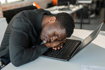 sleeping african man at work at laptop 