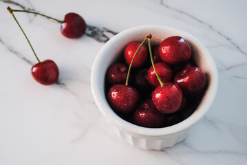 Ripe red cherries in a plate on the table. 