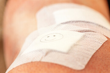 Adhesive bandage on a wound after am arthroscopy surgery with a happy smiley on the bandage