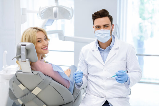 Patient and male doctor with dental tools looking at camera