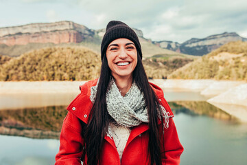 Portrait of cheerful smiling young female traveler in stylish clothing and beanie while standing...