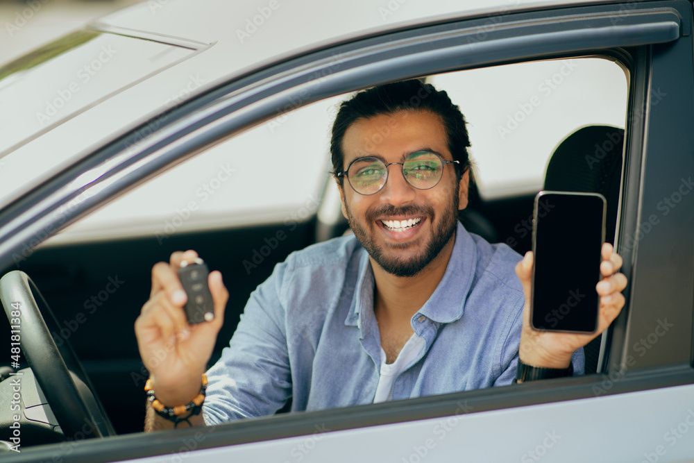 Wall mural Cheerful middle-eastern guy showing car key and smartphone, moclup