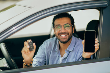 Cheerful middle-eastern guy showing car key and smartphone, moclup