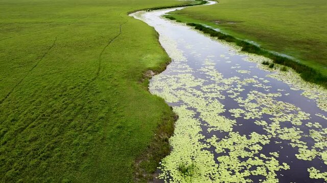 Reversal down stream river surrounded by vast open plain wetlands landscape at Ira Lalaro, Nino Konis Santana National Park, Timor Leste, aerial drone reversing