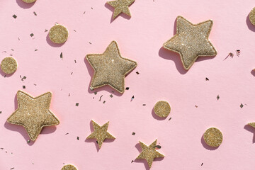 Golden decorative stars and sparkles on a pink background. Flat lay, place for text.