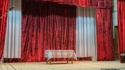 A theater stage with a table and red theater curtain. Art concepts.
