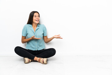 Teenager girl sitting on the floor with surprise facial expression