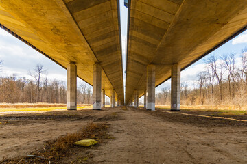Central view from under of highway bridge with high concrete pillars