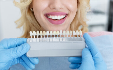 Dentist applying sample from tooth scale to patient white teeth