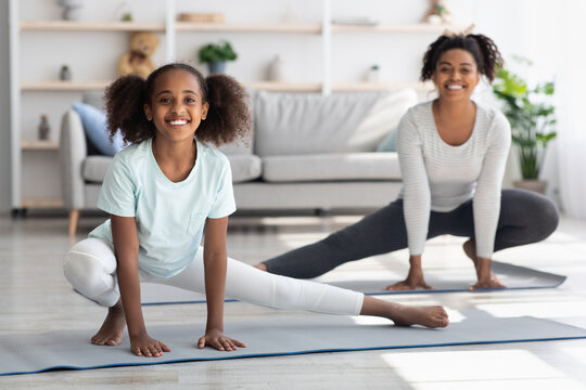 Joyful african american mother and daughter stretching at home