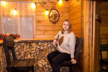 girl in a winter log cabin sitting by the window