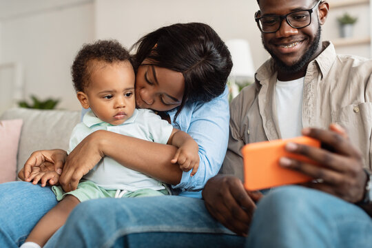 African american family using cellphone with baby at home