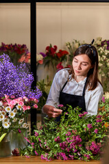 pretty caucasian florist making bouquet, experienced lady arranging spring flowers. lovely nice...