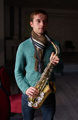 Fototapeta premium Young guy music artist jazzman holding a saxophone in his hands.