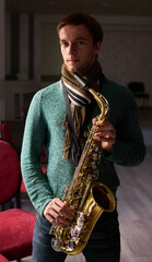 Fototapeta na wymiar Young guy music artist jazzman holding a saxophone in his hands.