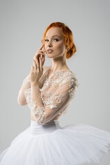 Alluring young ballerina in tutu touching face and looking at camera