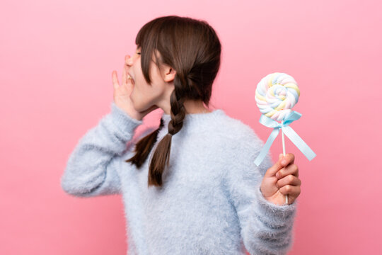 Little Caucasian Girl Holding A Lollipop Shouting With Mouth Wide Open To The Side