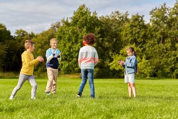 childhood, leisure and people concept - group of happy children playing tag game and running at park