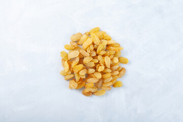 Yellow raisins on light grey background. Top view, copy space. Dried grapes fruit