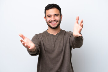 Fototapeta premium Young Brazilian man isolated on white background presenting and inviting to come with hand