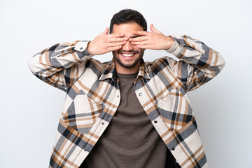 Young Brazilian man isolated on white background covering eyes by hands and smiling