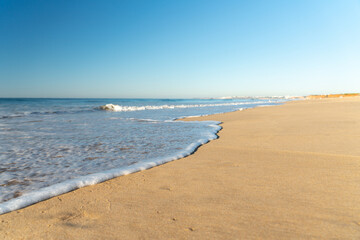 soft wave on the long sandy beach of Vilamoura in the Algarve in Portugal.