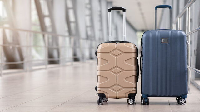 Two stylish suitcases standing in empty airport hall, panorama with copy space