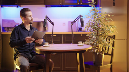 Male host on live podcast listening to plant guest in kitchen studio