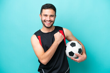 Young football player Brazilian man isolated on blue background celebrating a victory