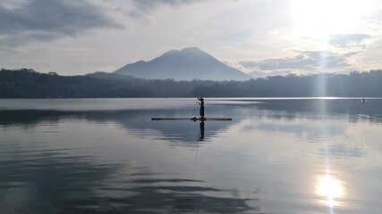 Obraz na płótnie Canvas Fisherman fishing on a beautiful volcanic caldera Lake Toba early in the morning