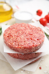 Raw hamburger patties with rosemary and salt on board, closeup
