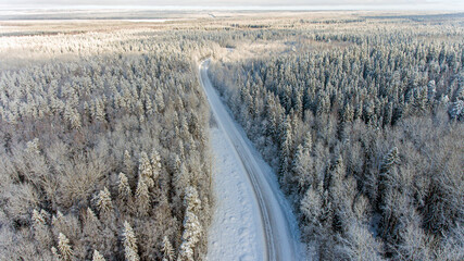winter road in the middle of a snowy forest from a height