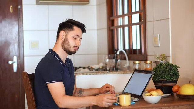 Man working on laptop and partner holds and kiss the other. Gay couple kiss each other in the morning in home office.
