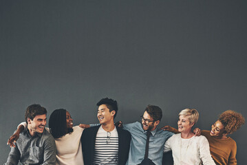 We make a great team. Studio shot of a diverse group of creative employees embracing each other...