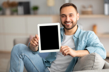 Happy young man showing tablet computer with mockup for website or application on screen, indoors