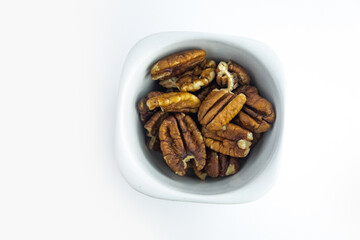 Pecan nuts in ceramic plate isolated on white background