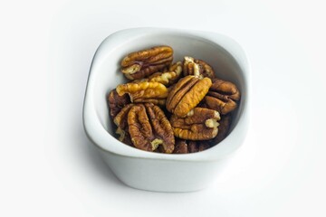 Pecan nuts in ceramic plate isolated on white background