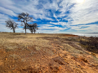 Wide angle view the sandstone cliff and rocky shoreline with picnic area bluffs overlooking lake at Murrell Park, Grapevine Lake, Texas