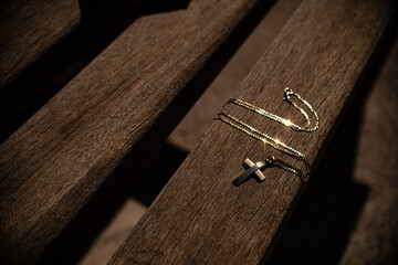 Silver christian cross on wooden bench