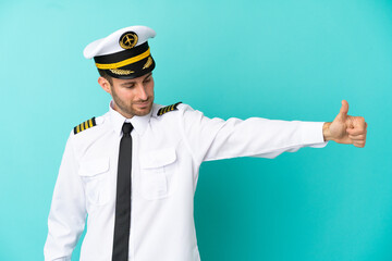 Airplane caucasian pilot isolated on blue background giving a thumbs up gesture