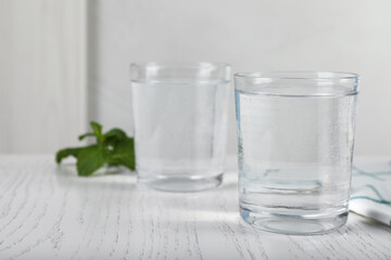 Glasses of soda water on white wooden table. Space for text