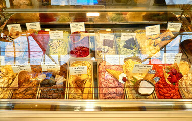 An ice cream display with different types of ice cream and names in Polish.