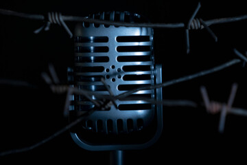 Close up microphone behind barbed wire as a symbol of discrimination, free speech crisis, political...