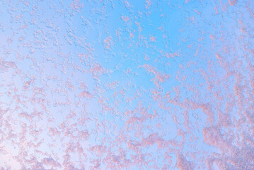 window glass with frosted snowflakes, pink shine of sunset mood